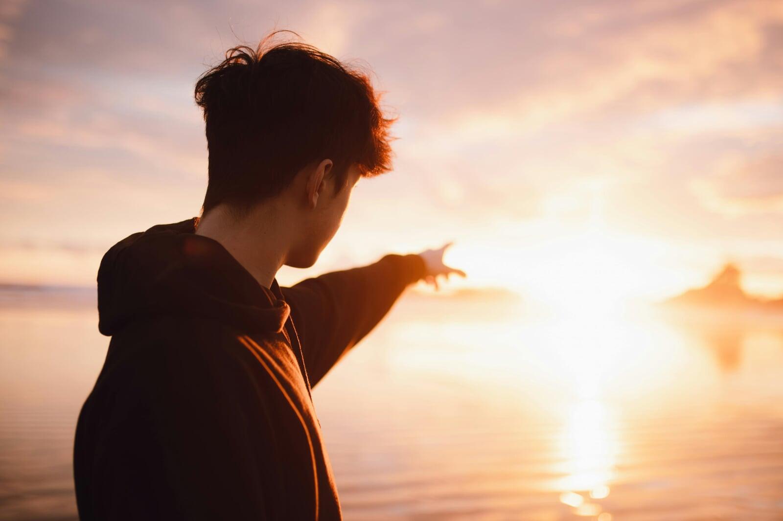 Man pointing at sunrise horizon - DMF vision: founders seeing business signals before it's too late